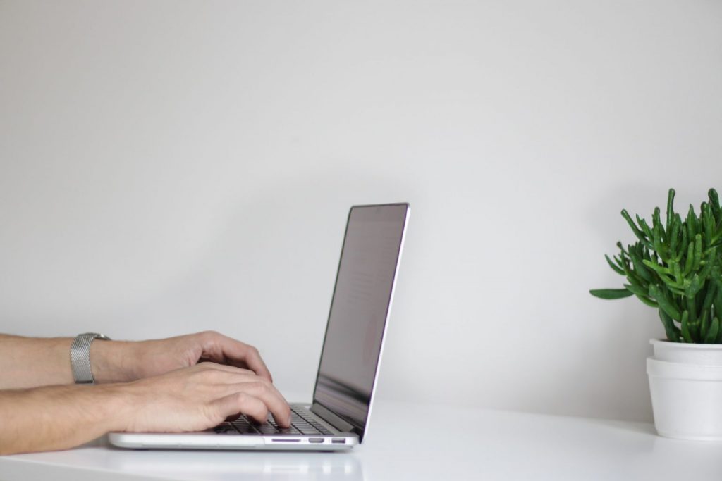 Person typing on computer with white background