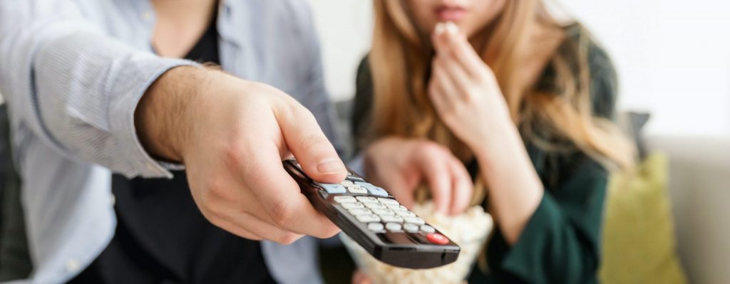 Couple sitting on couch pointing remote at screen