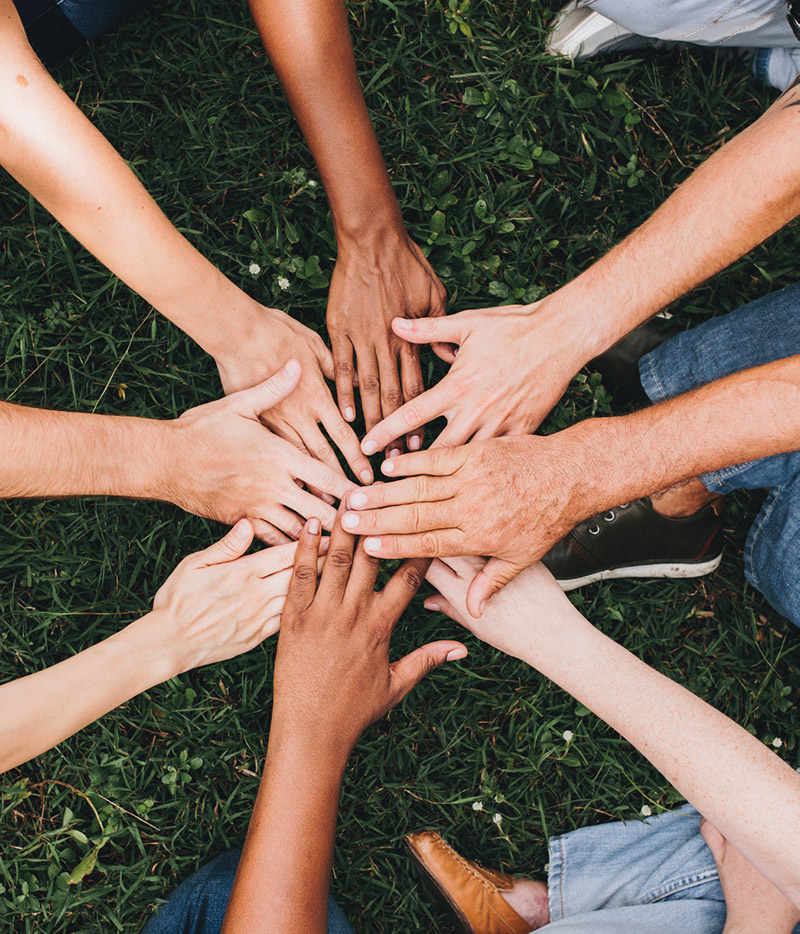 Hands put together in the middle of a circle